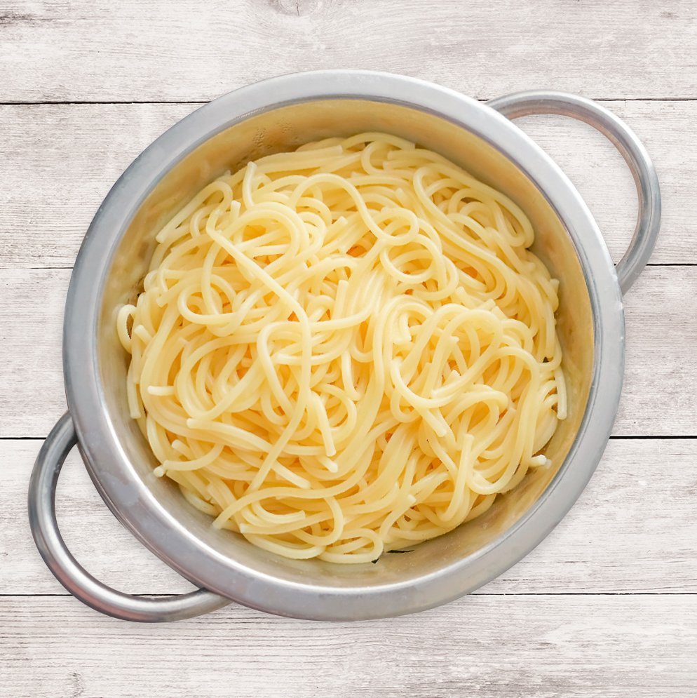 Ein Topf mit Spaghetti, welcher auf einer Holzplatte steht.