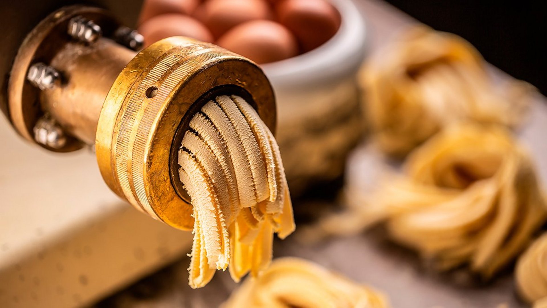 Frisch hergestellte breite Pasta wird aus einer Nudelmaschine gepresst