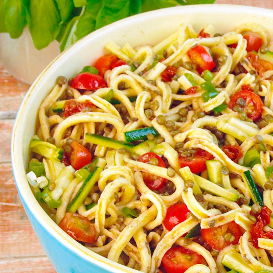 Spaetzle lentil salad with chopped tomatoes, green onions, and herbs in a white bowl
