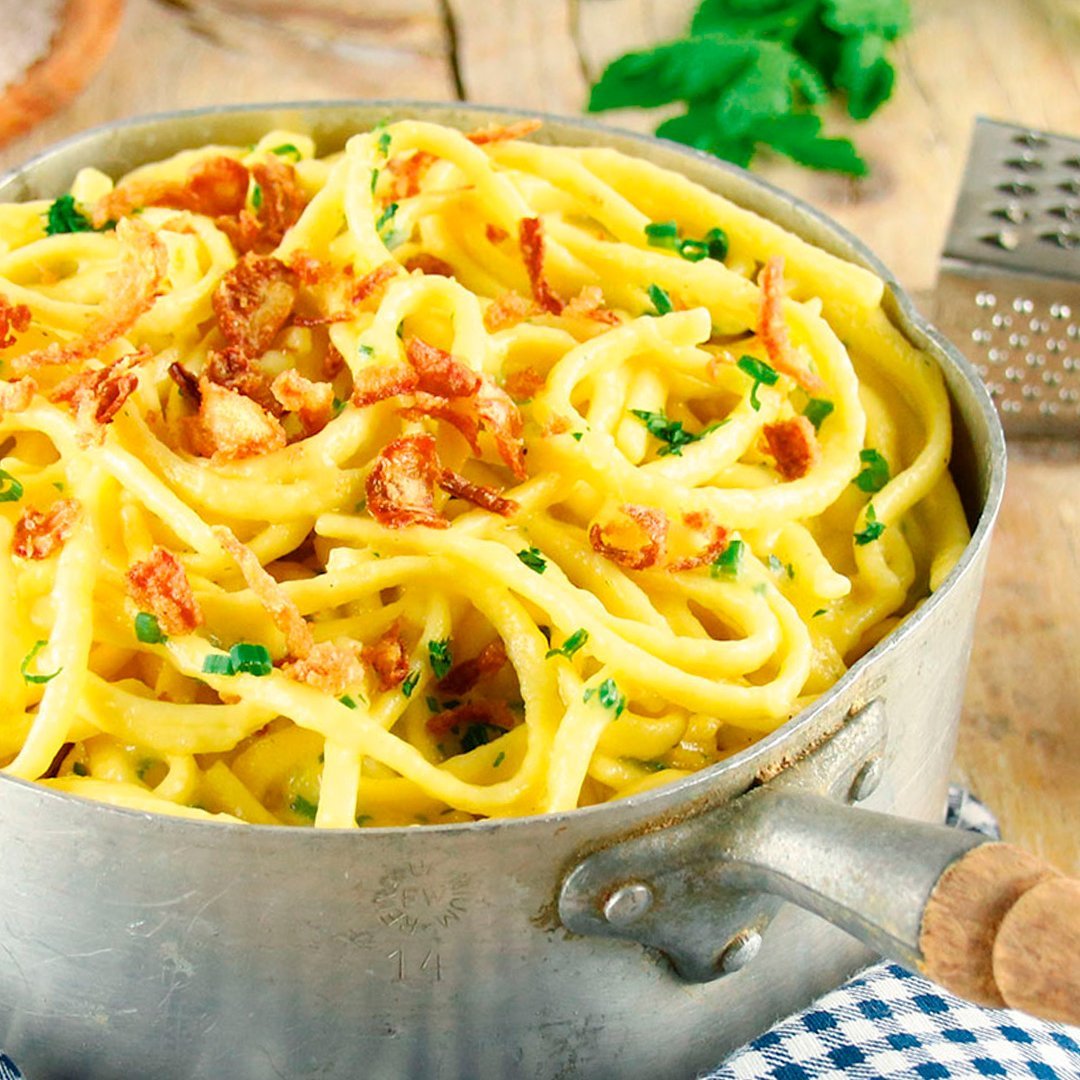 Herbs-cheese spaetzle topped with crispy fried onions in a metal pan